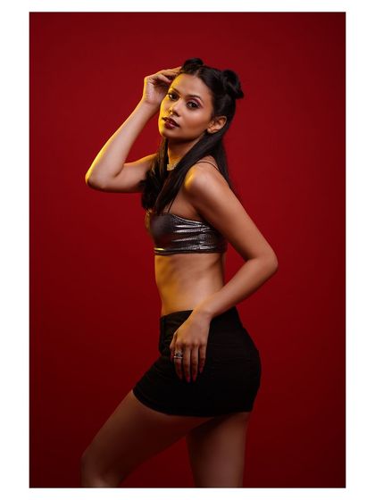 A classic pose against the vibrant red, highlighting the metallic top and the model's confident attitude.