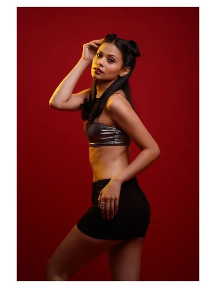A classic pose against the vibrant red, highlighting the metallic top and the model's confident attitude.