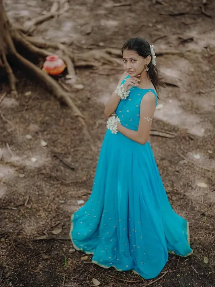 An overhead shot capturing the model in her flowing blue dress, creating a beautiful composition against the earthy ground.