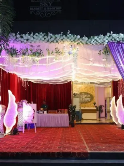 The entrance decoration for Sky Banquet hall's outdoor dining area in Kharghar. The setup features a red carpet, illuminated angel wings, and elegant purple drapes.