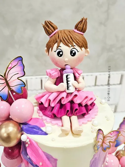 A close-up of the hand-sculpted girl figurine with pigtails and a pink dress.