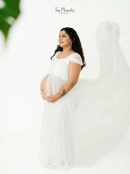 Framed by soft greenery, this portrait in the white flowing gown feels fresh, serene, and full of life.