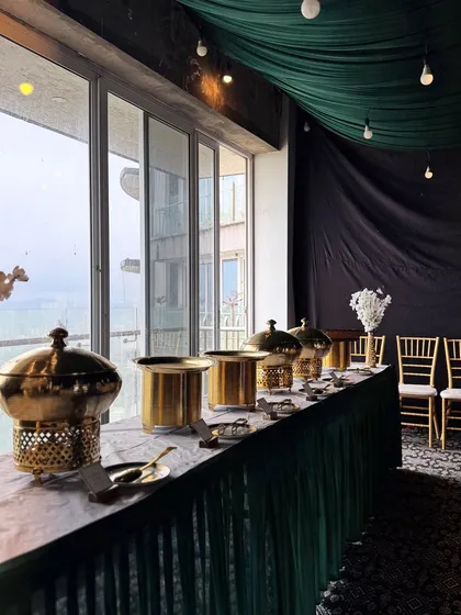 Our full-service catering includes creating a sophisticated ambiance. Here, you can see our elegant brass chafing dishes and coordinated green and gold decor, which we set up to ensure your event looks as incredible as the food tastes.