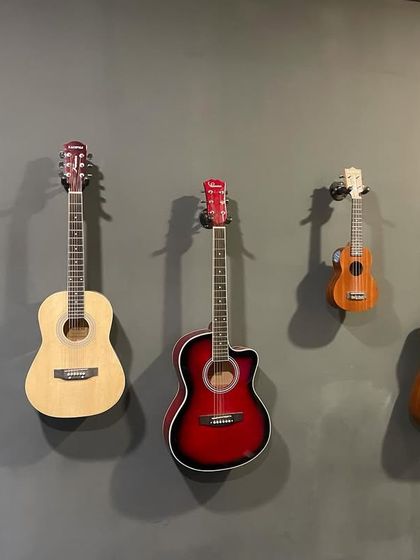 A selection of our school's instruments, including acoustic guitars and a ukulele, mounted on the wall and ready for any student to pick up and play.