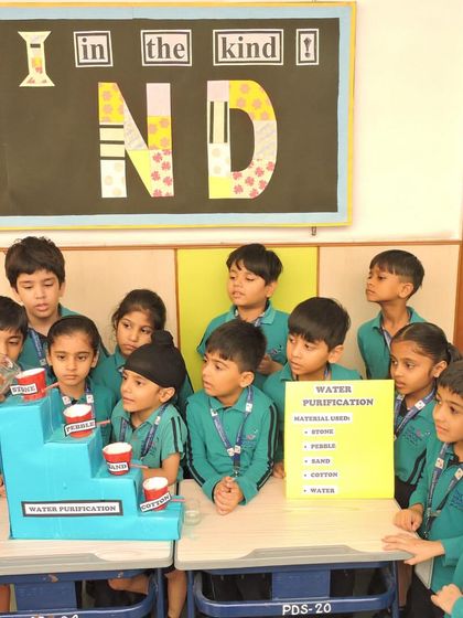 A student takes the lead and pours water into the filtration model, learning about the process of cleaning water through direct, hands-on participation.