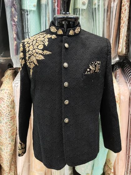 A close-up of the black Jodhpuri suit with gold leaf embroidery, displayed on a mannequin to highlight the craftsmanship.