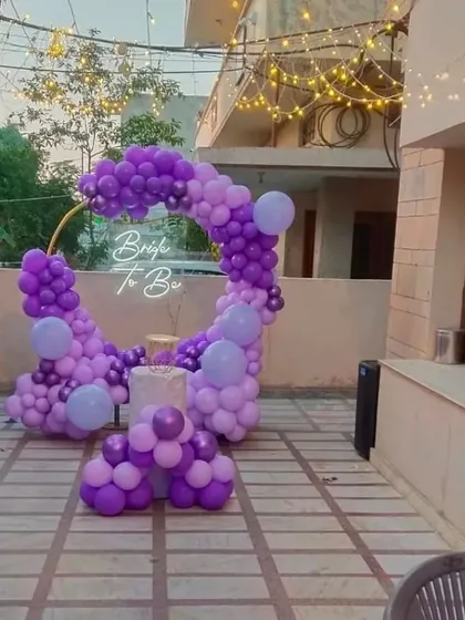 A 'Bride to Be' party on a terrace. This setup features a circular balloon arch in shades of purple with a neon sign, perfect for an evening celebration.