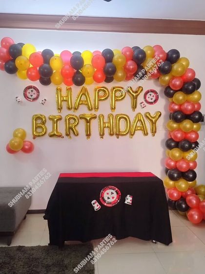 A casino-themed birthday decoration with a black, red, and yellow balloon arch.