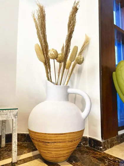 The 'Kerok' vase, with its white pitcher shape and natural bamboo base, is perfect for styling a cozy corner with dried grasses.