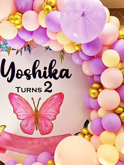 A close-up of a butterfly-themed second birthday backdrop, with a soft pastel balloon arch.