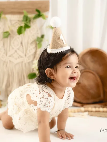 A candid crawling shot from a bohemian-inspired first birthday session. The natural textures and light colors create a warm, earthy feel.