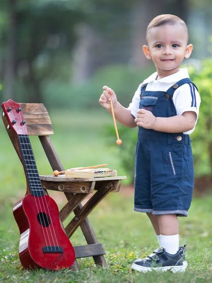 Let's play some music. This little boy is standing proudly with his guitar and xylophone, a perfect portrait from his musician-themed session.