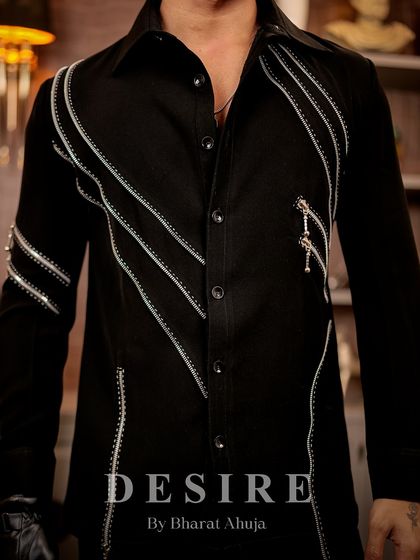 A close-up of the silver zipper detailing on the black shirt. The combination of embroidery and hardware creates a unique, textured look.