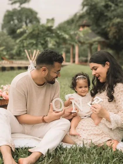 A candid moment during an outdoor family session, spelling out "ONE" for their daughter's first birthday.