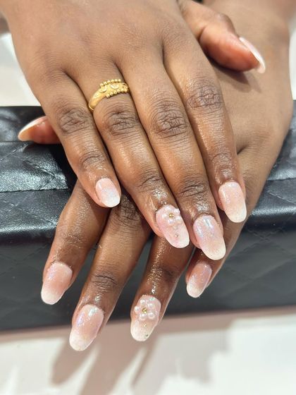 This design features a soft, milky white ombre with a subtle shimmer. Tiny pearl clusters on the accent nails add a touch of sophistication.