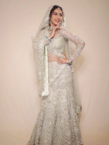A full-length shot of this stunning pastel creation. The mermaid-style lehenga and long-sleeved blouse are the epitome of modern bridal fashion.