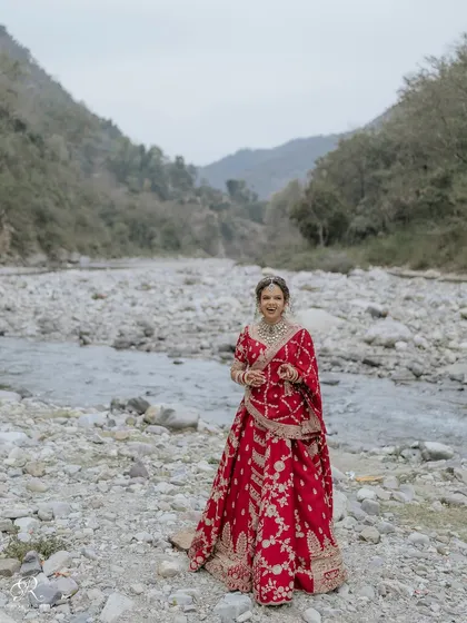 A duplicate of ID 1, a stunning full-length portrait of the bride in her red lehenga against the Rishikesh landscape.
