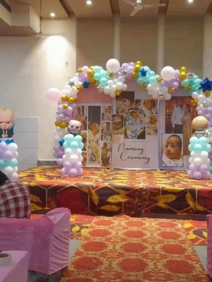 The final stage setup for a 'Naming Ceremony' with a Boss Baby theme, featuring a custom photo backdrop and a pastel balloon arch.