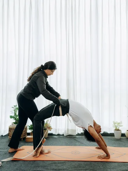 This is an advanced adjustment for Urdhva Dhanurasana (Wheel Pose) using a belt. This technique helps the student to open the shoulders and lift the chest higher, achieving a deeper backbend with support and control.