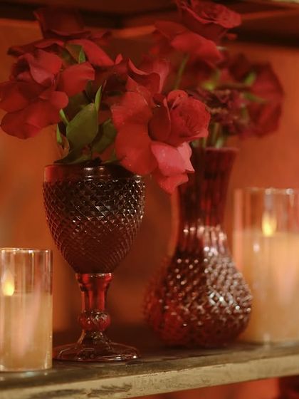 An even tighter shot of the bar back, focusing on the texture of the red glassware and the soft light of the candles.