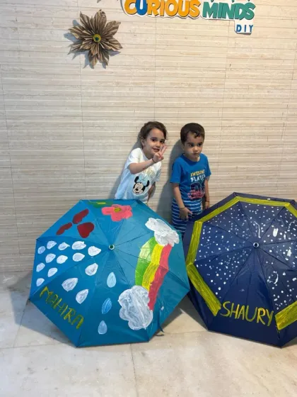 Two of my youngest students posing with their finished umbrellas. One chose a rainy day rainbow theme, while the other created a starry night sky.