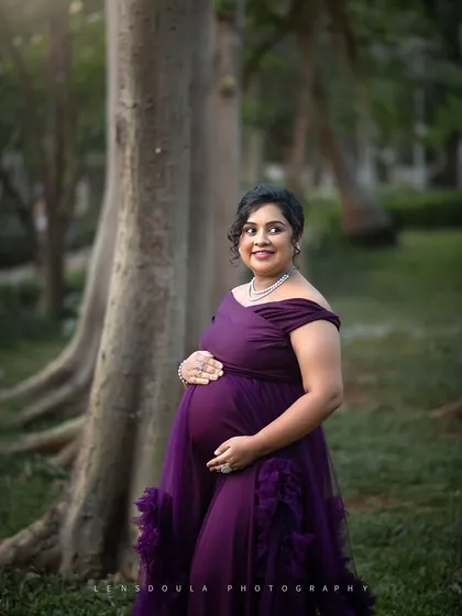 A quiet moment of reflection for the mother-to-be, cradling her bump in a peaceful, wooded setting.