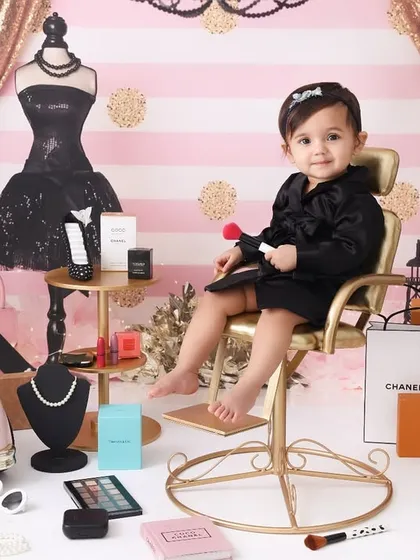 Born with style. This fashion-themed shoot, inspired by high-end brands like Chanel, is perfect for a little trendsetter. The setup includes glamorous props for a chic and playful portrait.