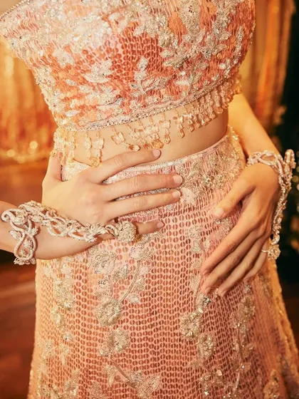 A close-up on the details of the pink sequined Manish Malhotra lehenga, showing the incredible craftsmanship and hand jewelry that completed this iconic look.
