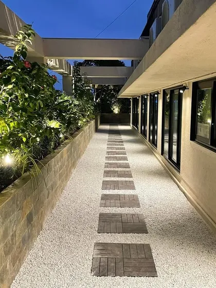 A long shot of the revamped corporate terrace at dusk. The linear path with embedded lights guides the eye and creates a sense of length, while the illuminated planters add warmth and drama.