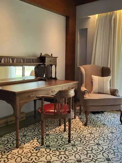 An antique-style writing desk and chair create a charming workspace in the Alibaug villa. The design blends traditional furniture with modern patterned flooring, overlooking the pool area.