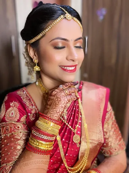 A candid moment capturing the intricate details of the bride's Phera look, from her henna-adorned hands to her perfectly applied makeup.