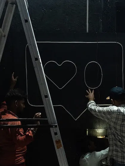 Behind the scenes of the 'Surfing' installation at MUAF. Here, my team and I are mounting the framework for the neon sign against a black brick wall.