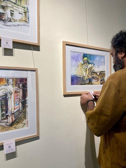 Another shot of the setup process. Getting every painting perfectly hung is a crucial part of presenting the art.