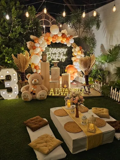 My bohemian picnic setups are perfect for a relaxed and stylish celebration. This birthday party features low seating with comfortable cushions, a beautiful balloon arch in earthy tones, and a personalized neon sign, all arranged for a cozy gathering.