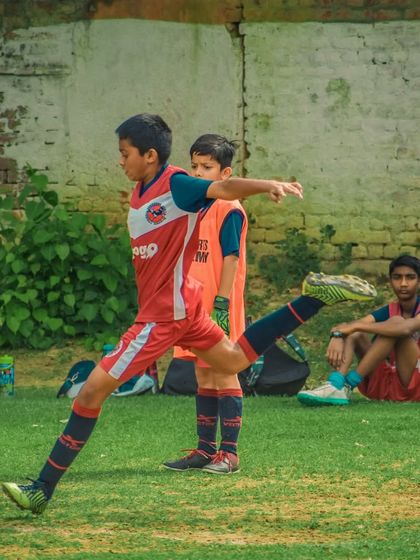 A player warms up with a stretch kick on the sidelines before a match.