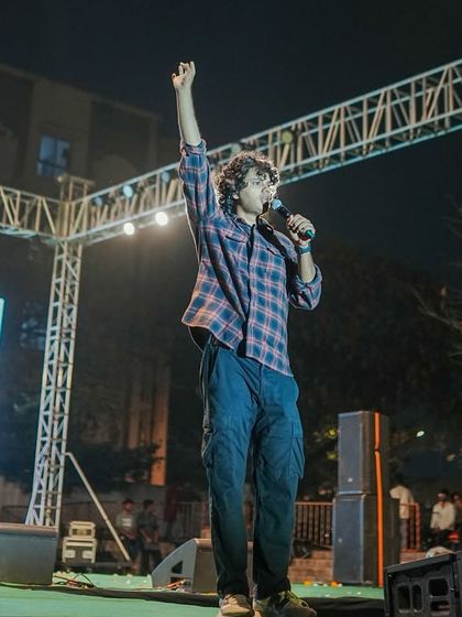 Joel D'souza raising his hand to energize the audience during his outdoor performance.