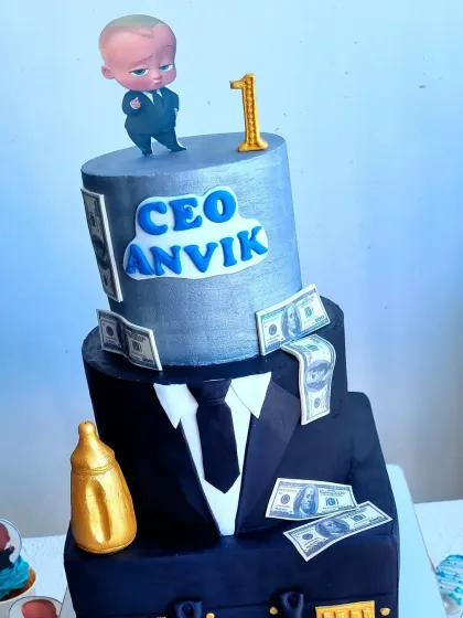 A close-up of a three-tier Boss Baby cake. This sculpted cake features a suit, a briefcase, and a "CEO" nameplate, perfect for a first birthday.