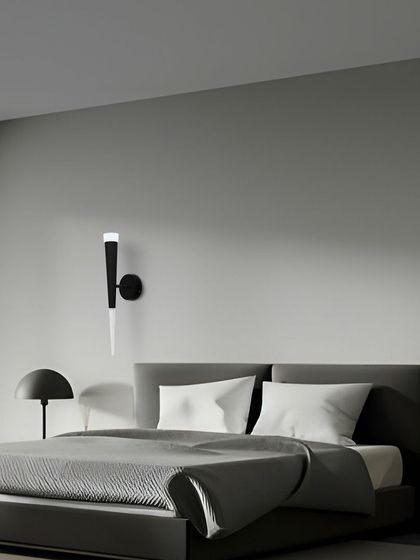 This torch-style wall sconce provides a soft, ambient light that is perfect for creating a relaxing atmosphere in a bedroom.