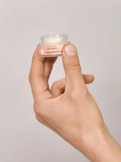 A hand holding a small jar of In'lief lip balm to show its compact size. This is useful for customers to understand the product's portability.