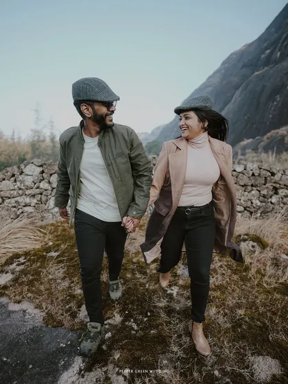 A vintage-style pre-wedding shoot in the hills. The couple's classic attire and the rustic stone wall create a timeless, storybook feel.