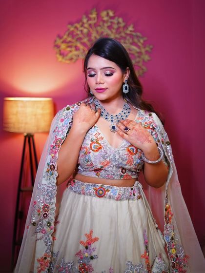 A close-up on the makeup and the stunning sapphire and diamond necklace that complements the floral embroidery.