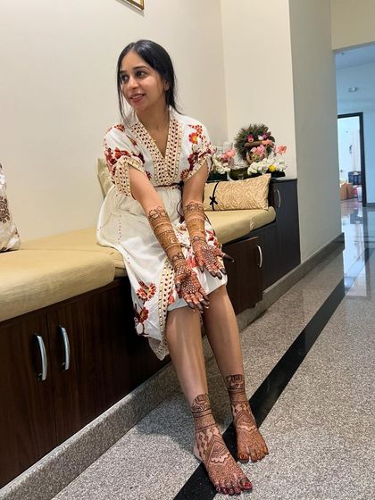 A beautiful bride, Maheshwari, relaxing after her mehendi session, with intricate designs on her hands and feet.