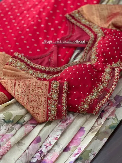 A closer look at the red blouse, detailing the gold embroidery and pearl work along the neckline and sleeves.