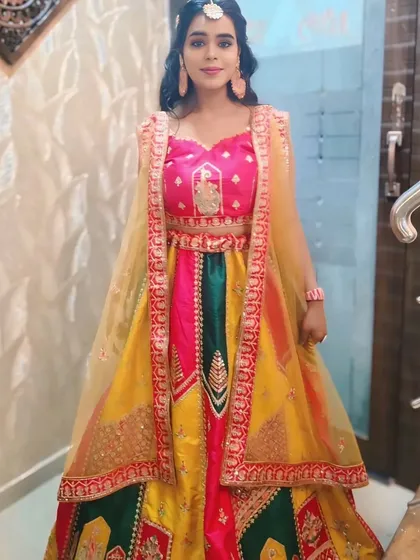 Another happy client looking radiant in a colorful lehenga, perfect for a Haldi or Sangeet event.