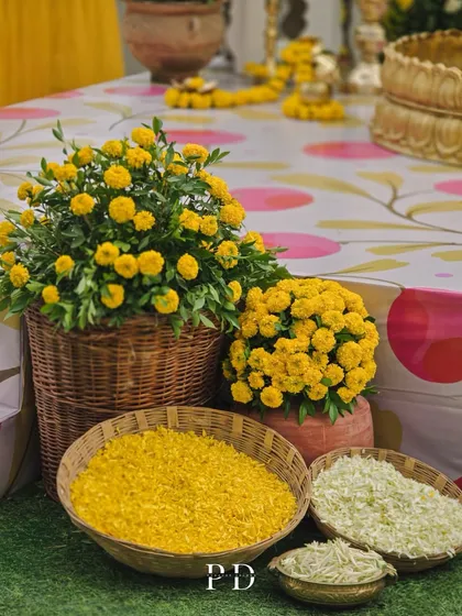 A traditional Haldi setup with baskets of marigolds and rice, ready for the ceremony. The printed tablecloth adds a pop of modern color.