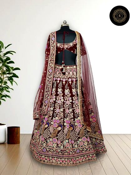 A deep maroon velvet lehenga with beautiful peacock embroidery. The details on this piece are what make it a truly special designer outfit for your wedding.