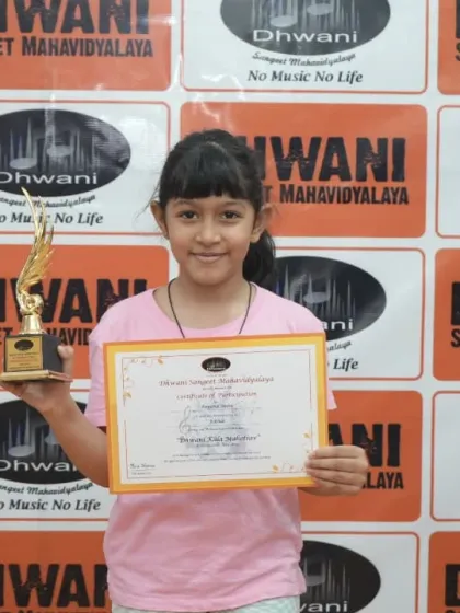 A young student proudly holds her certificate and award.