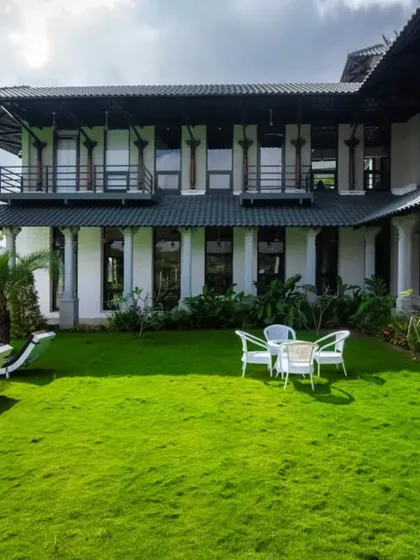 An expansive view of the farmhouse, its lawn, and the poolside lounge area, showcasing a complete luxury outdoor living experience.