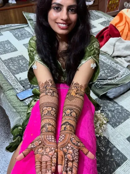 A smiling bride proudly presents her full-arm Rajasthani mehendi. The design is filled with traditional floral and animal motifs.