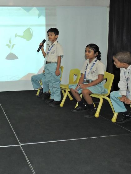 A student holds the microphone, focusing on the visual prompt on the screen as he prepares to spell his word. These competitions are designed to be fun and engaging.